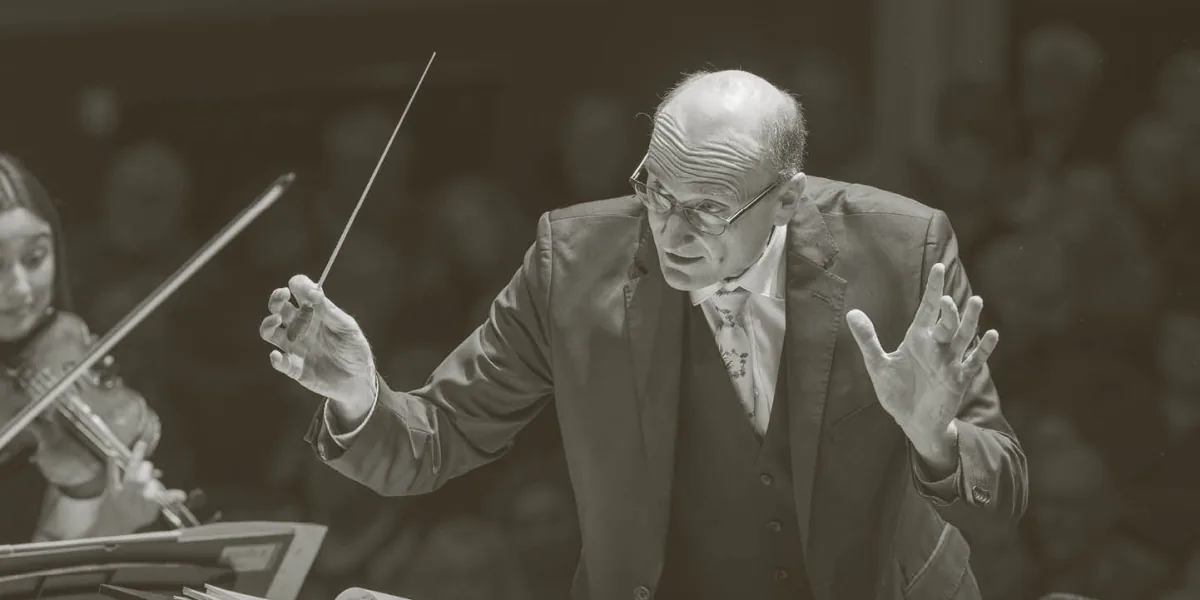 Andrew Manze conducts the orchestra, holding a baton